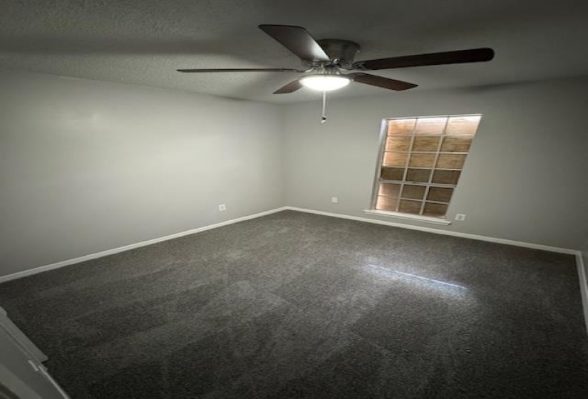 Carpeted spare room with a textured ceiling and baseboards
