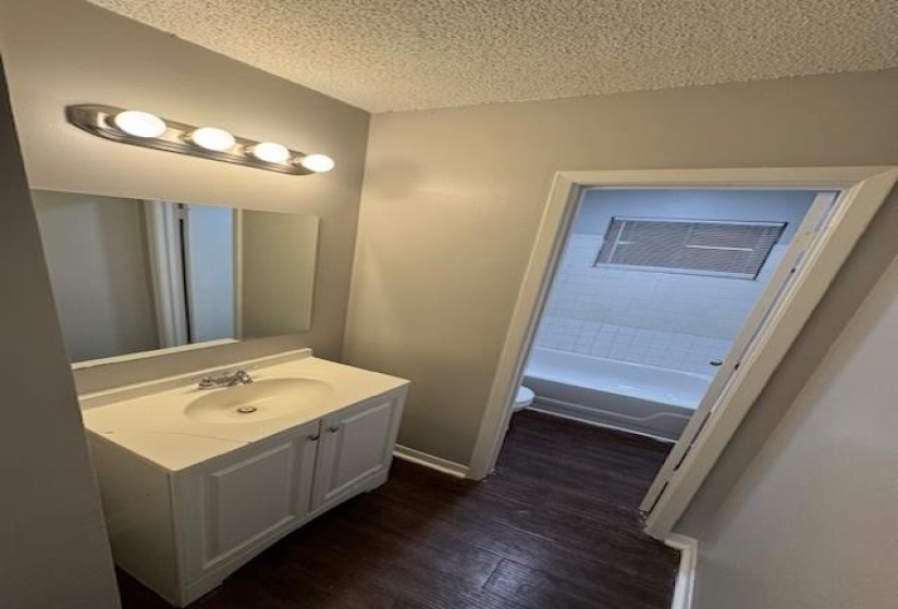 Full bath featuring vanity, a textured ceiling, and dark wood finished floors
