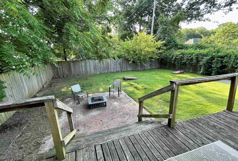 Wooden terrace with a patio area, a fenced backyard, and an outdoor fire pit