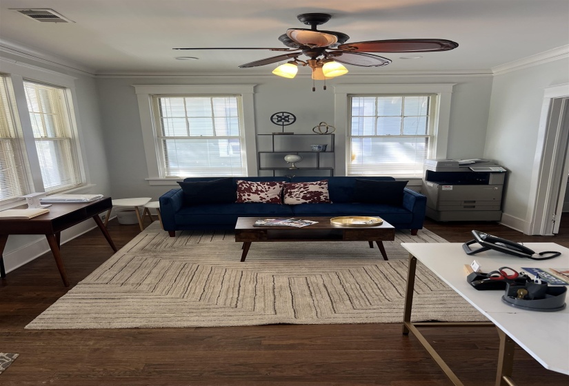 Living area featuring crown molding, a ceiling fan, and dark wood finished floors