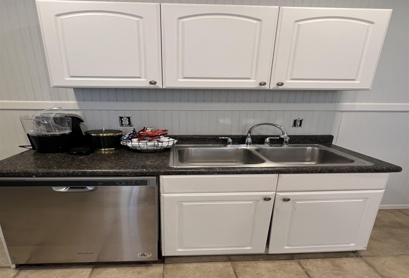Kitchen with dark countertops, white cabinetry, dishwasher, and light tile patterned floors