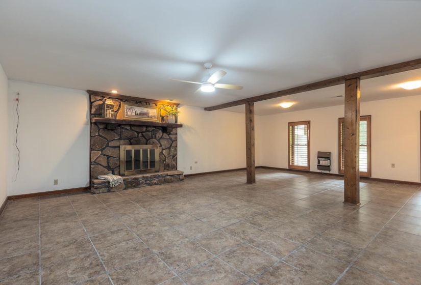 Unfurnished living room featuring a fireplace, heating unit, a ceiling fan, and beamed ceiling