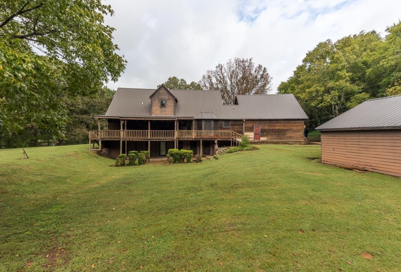 Back of property featuring a lawn, a metal roof, and a deck