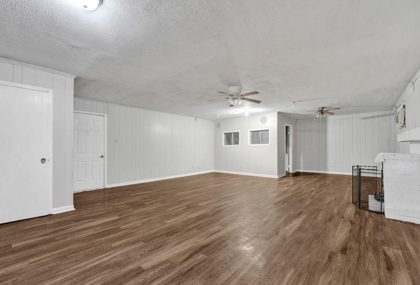 Unfurnished living room with wood finished floors, baseboards, a fireplace, ceiling fan, and a textured ceiling
