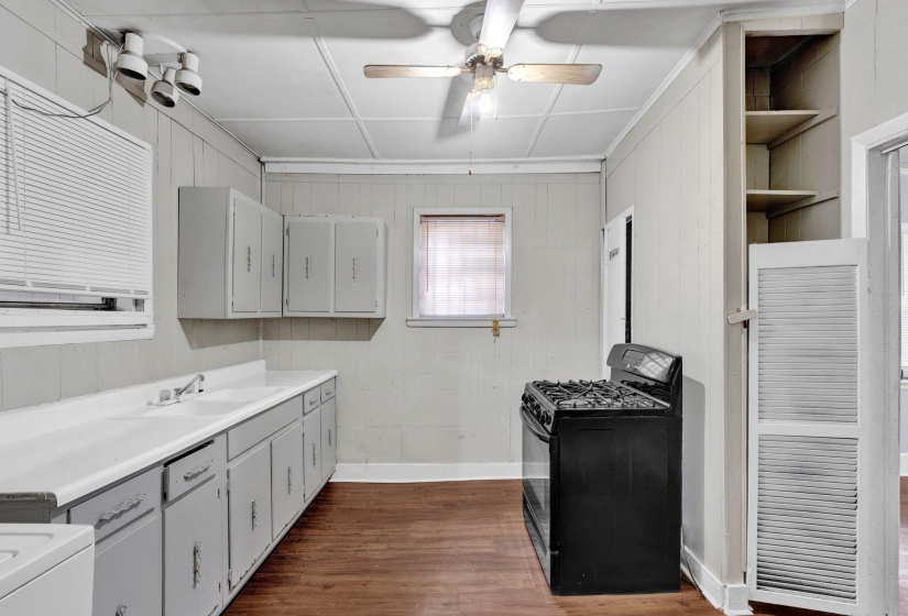 Kitchen featuring gas stove, dark wood-style flooring, ceiling fan, gray cabinetry, and a sink