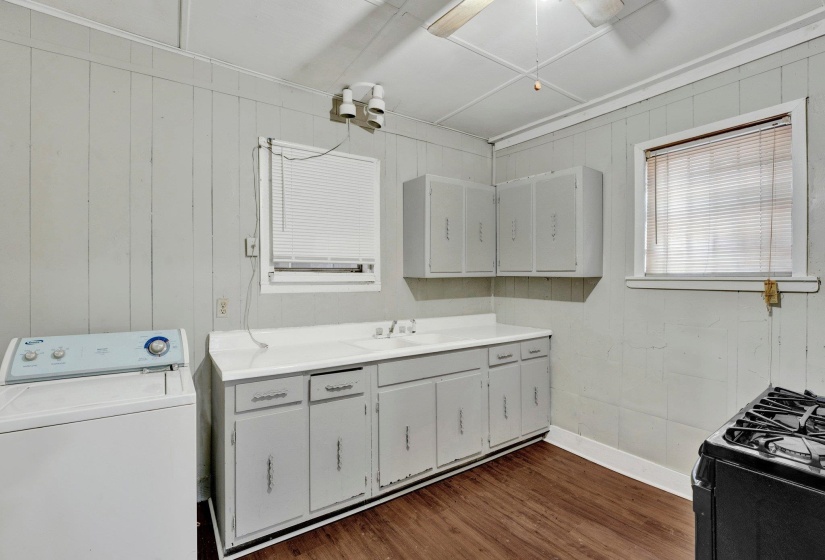 Clothes washing area with dark wood finished floors, laundry area, washer / clothes dryer, a ceiling fan, and a sink