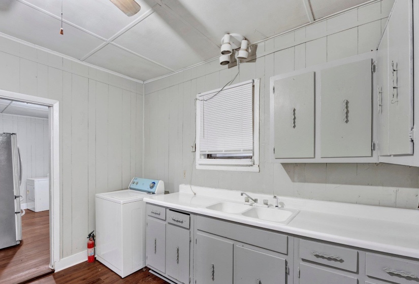 Laundry room with baseboards, washer / clothes dryer, cabinet space, dark wood-style flooring, and a sink