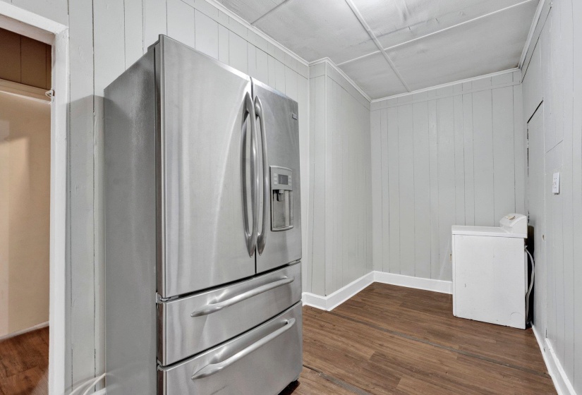 Kitchen featuring baseboards, washer / dryer, ornamental molding, dark wood-type flooring, and stainless steel refrigerator with ice dispenser