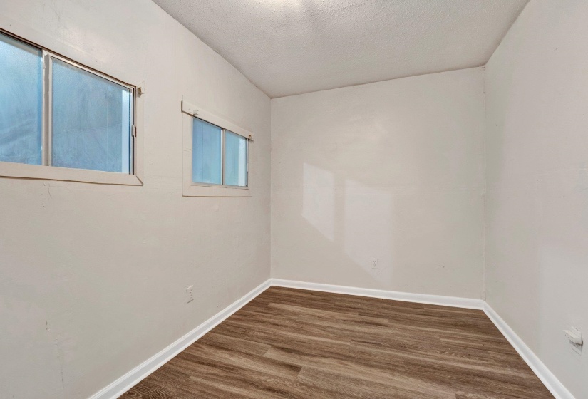 Spare room featuring a textured ceiling, baseboards, and wood finished floors