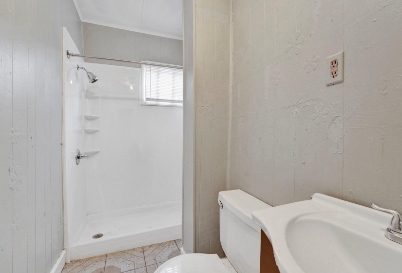 Full bath featuring a sink, toilet, wood walls, and a shower stall