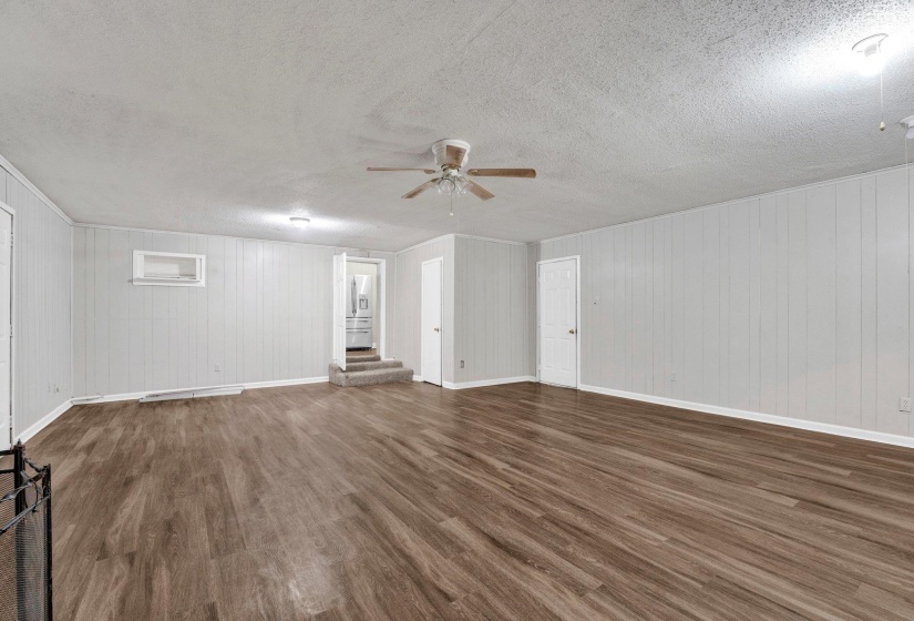 Unfurnished living room with baseboards, wood finished floors, a textured ceiling, and ceiling fan