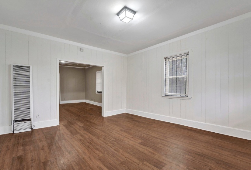 Unfurnished room featuring baseboards, wood finished floors, a heating unit, and crown molding