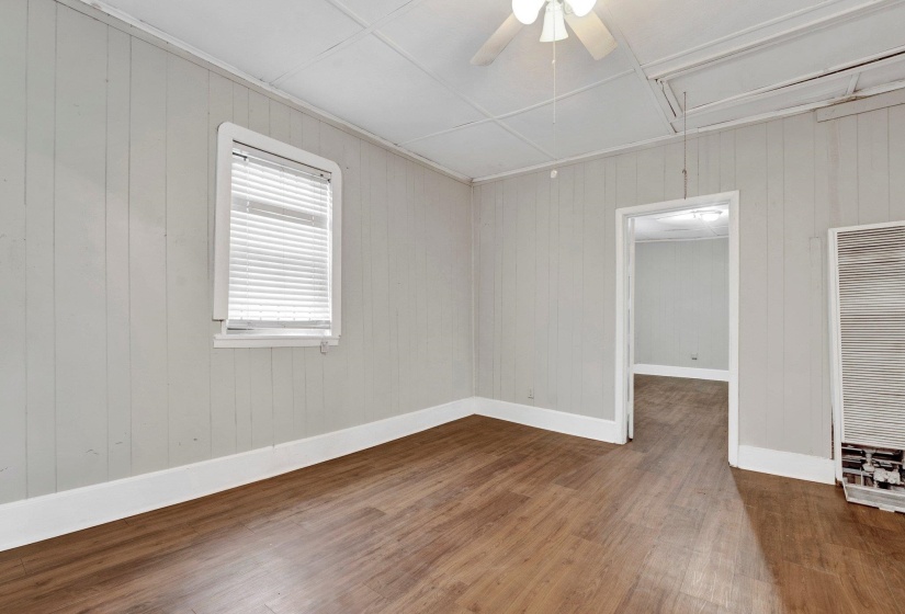 Unfurnished room featuring baseboards, attic access, wood finished floors, and a ceiling fan