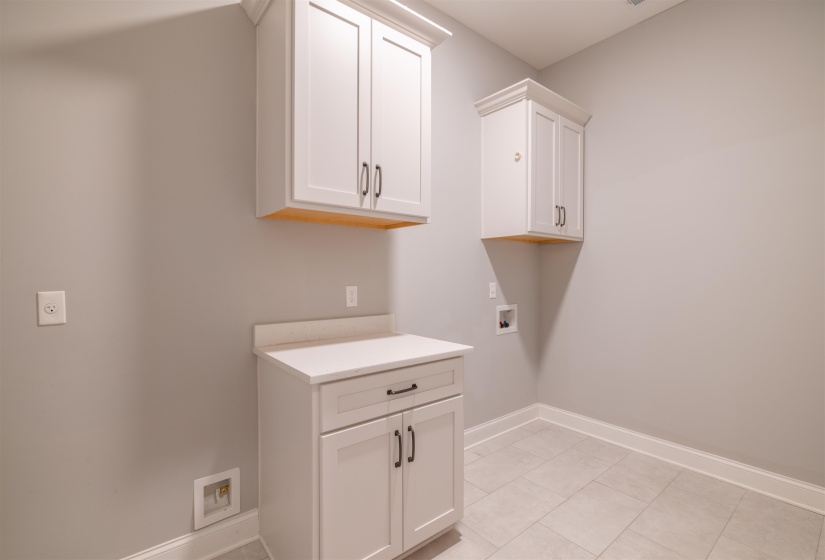 Washroom featuring washer hookup, cabinet space, and light tile patterned floors