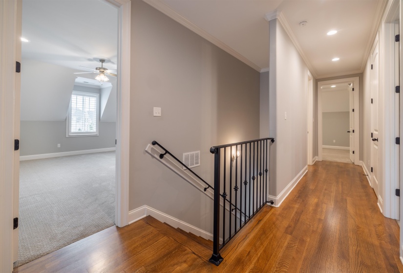 Corridor featuring an upstairs landing, recessed lighting, light wood-style floors, light carpet, and ornamental molding