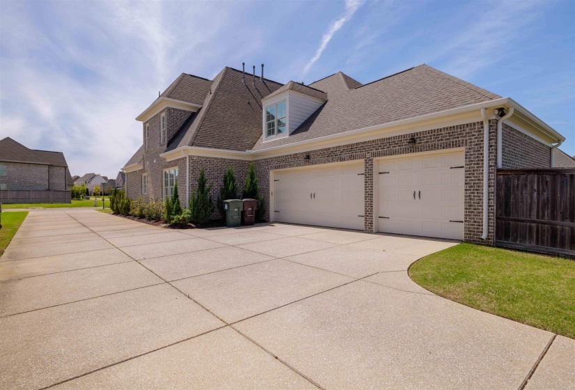 View of home's exterior with driveway, brick siding, a garage, and roof with shingles