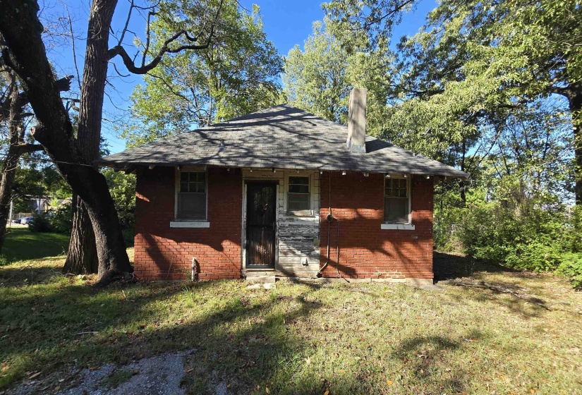 Back of house with a yard, a chimney, and a shingled roof