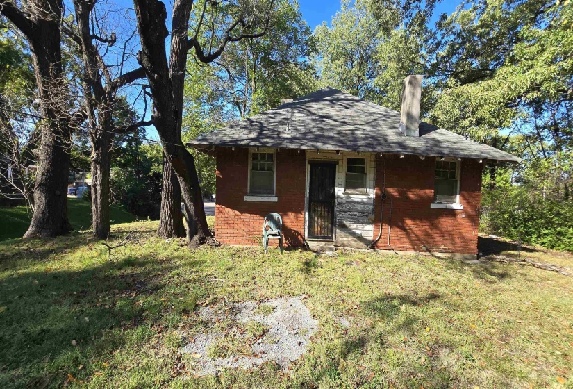 Back of property with a yard, a chimney, brick siding, and roof with shingles
