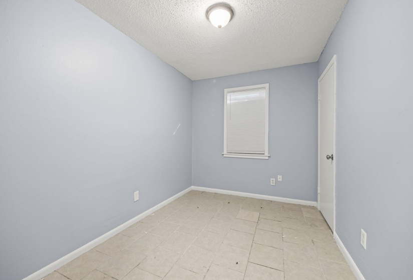 Unfurnished room with a textured ceiling and light tile patterned flooring