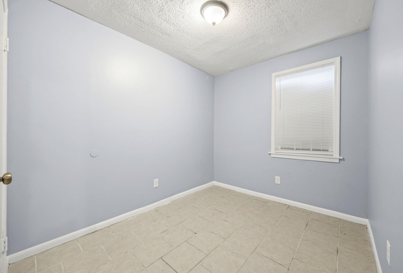 Unfurnished room featuring a textured ceiling and light tile patterned flooring