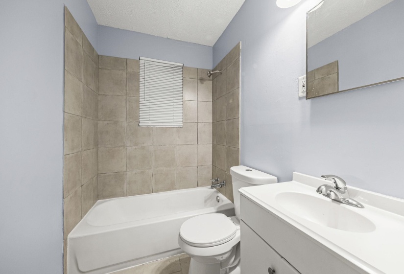 Bathroom with bathtub / shower combination, vanity, a textured ceiling, and tile patterned flooring