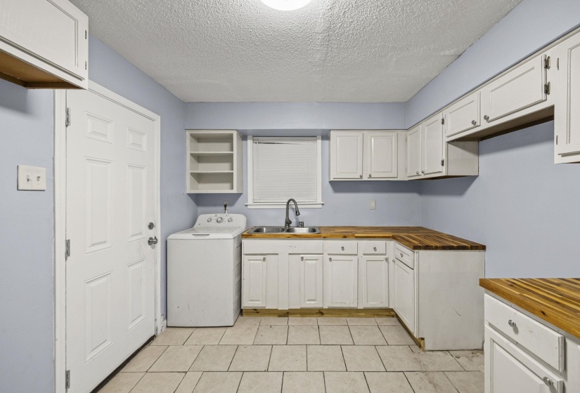 Laundry room featuring washer / clothes dryer, a textured ceiling, cabinet space, and light tile patterned floors