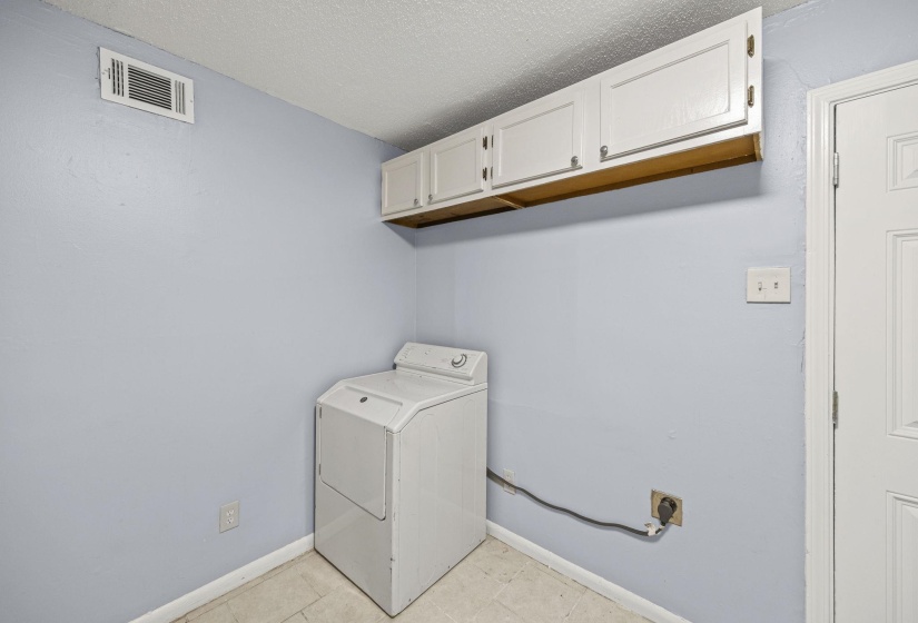 Laundry room featuring washer / clothes dryer, a textured ceiling, light tile patterned flooring, and cabinet space