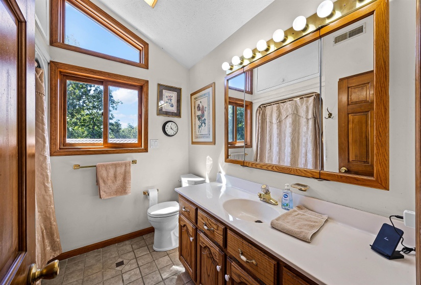 Bathroom with vanity, light tile patterned floors, a textured ceiling, lofted ceiling, and a shower with shower curtain