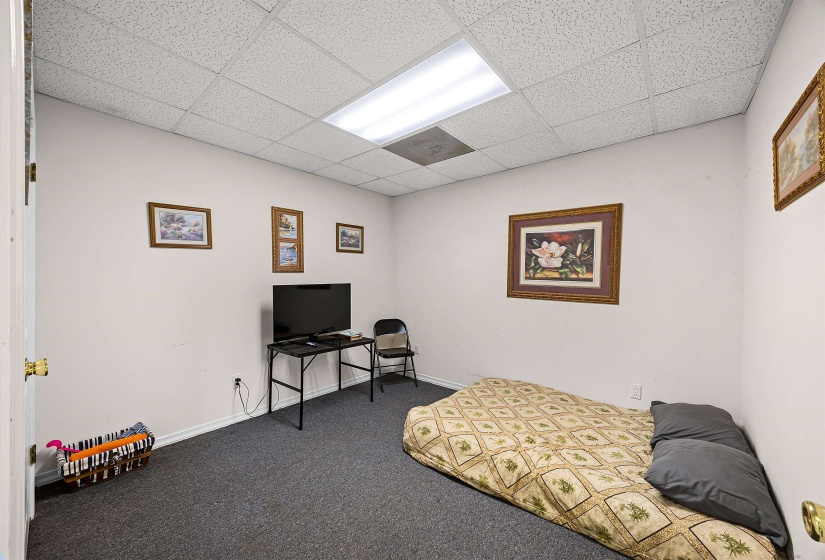 Carpeted bedroom with a drop ceiling and baseboards