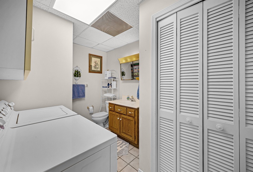 Laundry room with light tile patterned floors, a paneled ceiling, and washer and clothes dryer