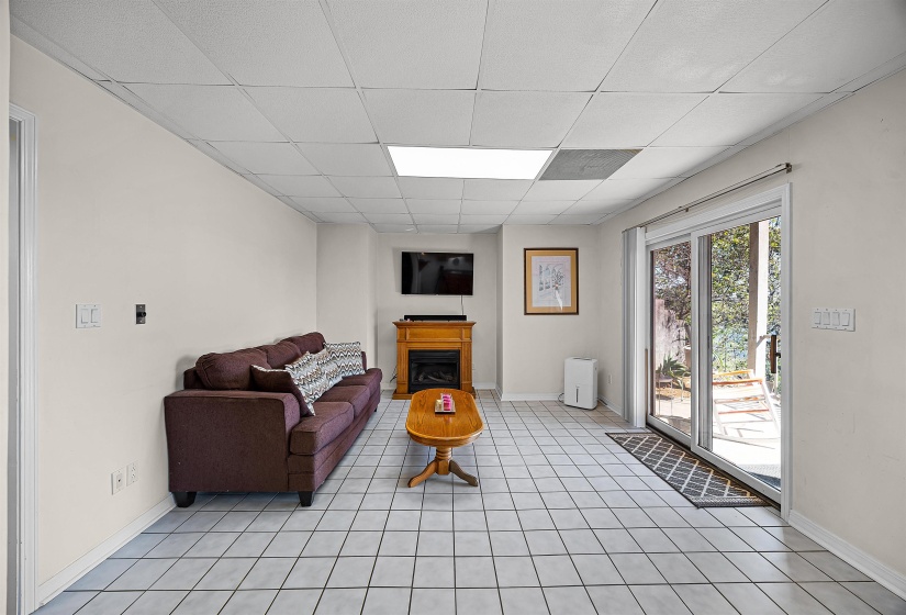 Living area featuring a drop ceiling, a fireplace, and light tile patterned floors