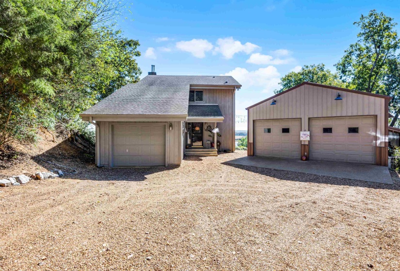 View of front of house with an outdoor structure, a shingled roof, and a detached garage