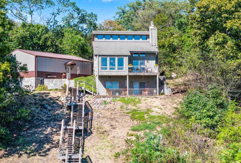 Rear view of house with stairs, a chimney, and view of wooded area