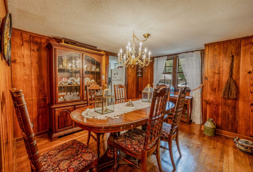 Dining room with wood walls, a textured ceiling, a chandelier, and wood-type flooring