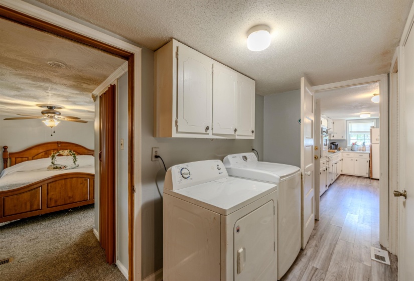 Clothes washing area featuring cabinet space, a textured ceiling, independent washer and dryer, a ceiling fan, and light wood-style floors