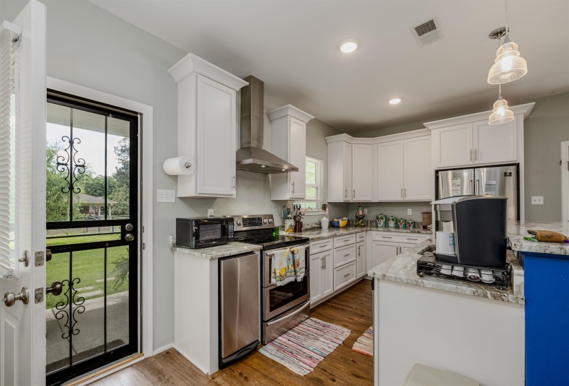 Kitchen featuring wall chimney range hood, appliances with stainless steel finishes, plenty of natural light, white cabinetry, and recessed lighting