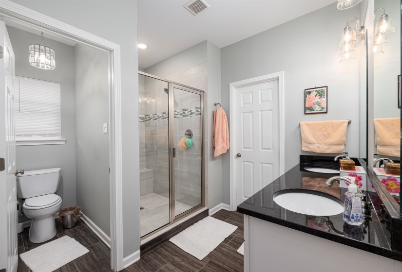 Bathroom with wood tiled floors, a stall shower, baseboards, and toilet