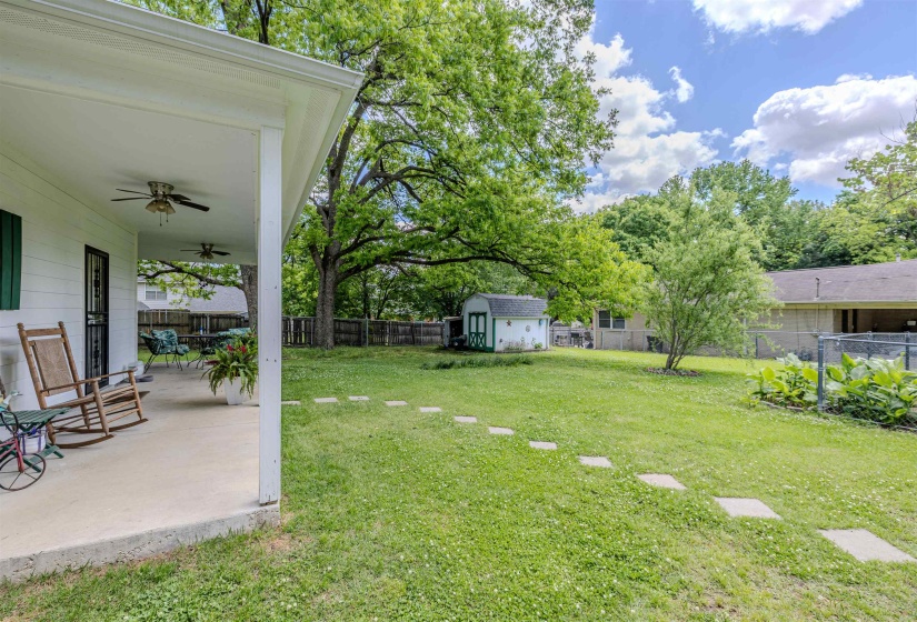 View of yard with a ceiling fan, a storage unit, a patio area, and an outdoor structure