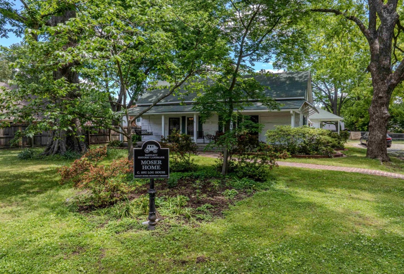 View of property hidden behind natural elements with a shingled roof