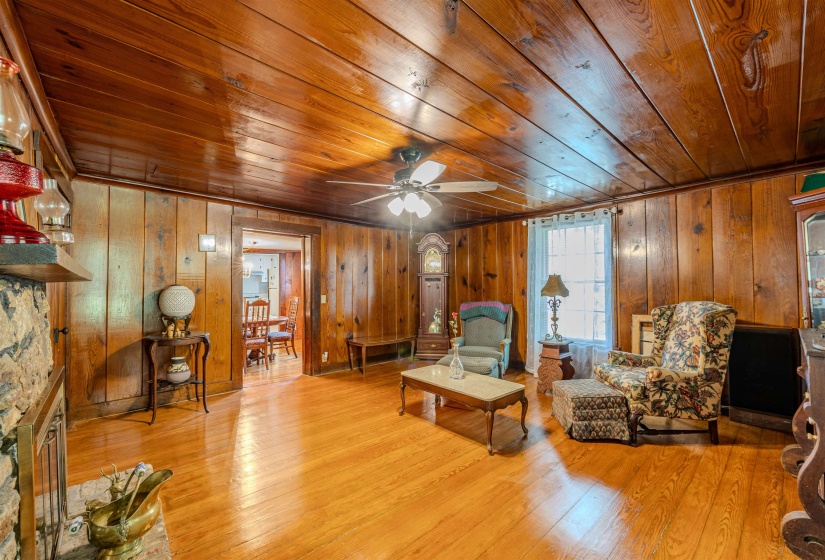 Living area with wooden ceiling, wooden walls, wood finished floors, and ceiling fan