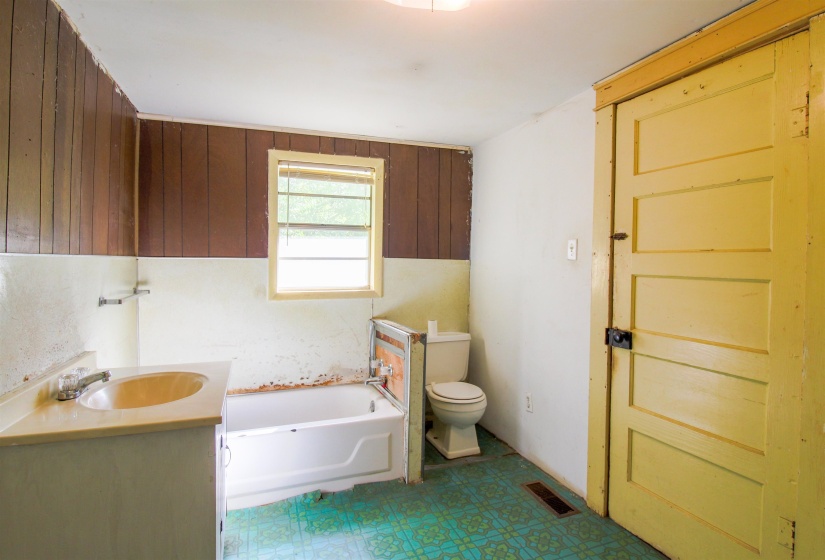 Bathroom with a bath, vanity, dark flooring, and wood walls