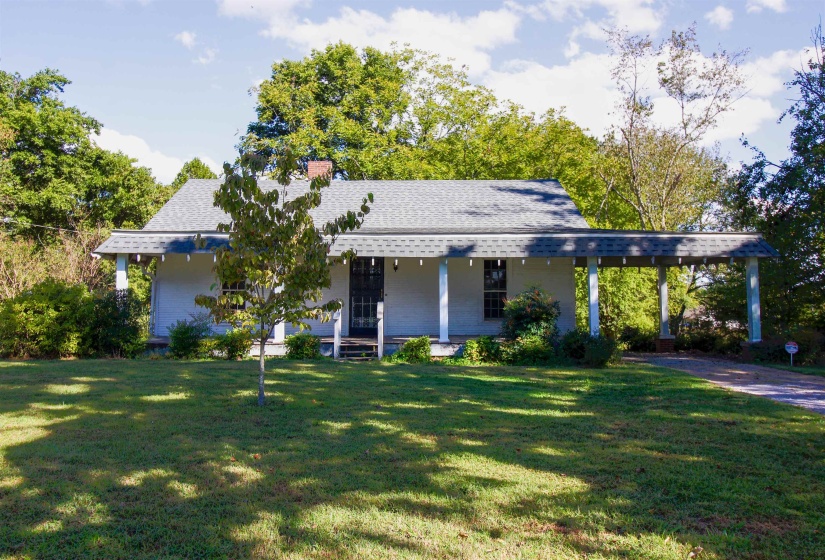 View of front  covered porch, a front yard, a carport, and fruit trees.