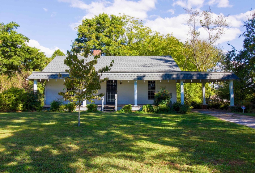 View of front of house featuring covered porch, a front yard, roof with shingles, and an attached carport