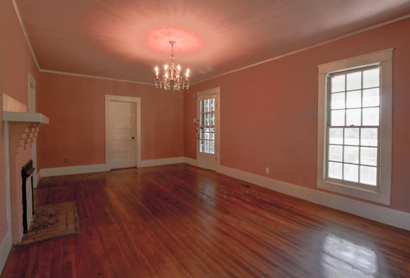 Living room featuring ornamental molding, a brick fireplace, original hardwood floors , and a chandelier