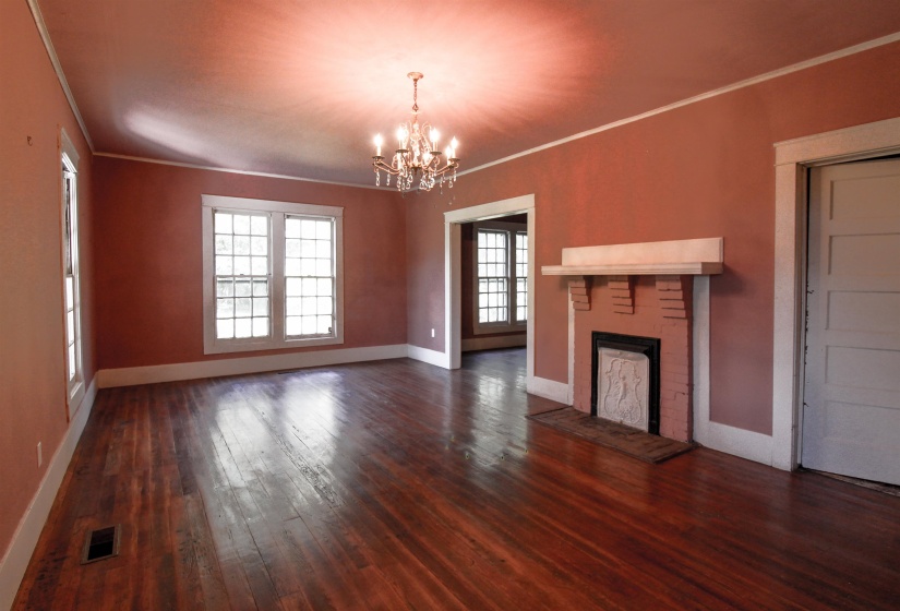 Living room featuring ornamental molding, a brick fireplace, original hardwood floors , and a chandelier and crown molding.