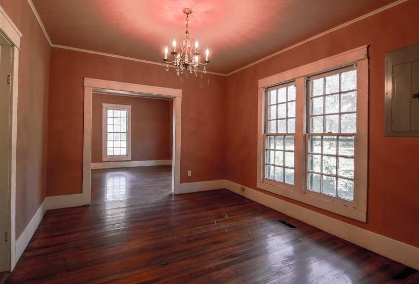 Dining room featuring ornamental molding, a brick fireplace, original hardwood floors , and a chandelier and crown molding.