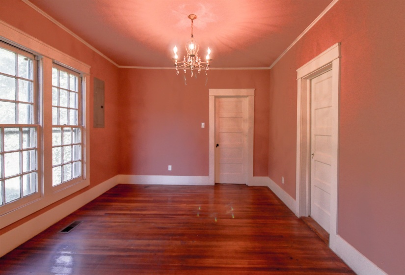 Dining room featuring ornamental molding, a brick fireplace, original hardwood floors , and a chandelier and crown molding.