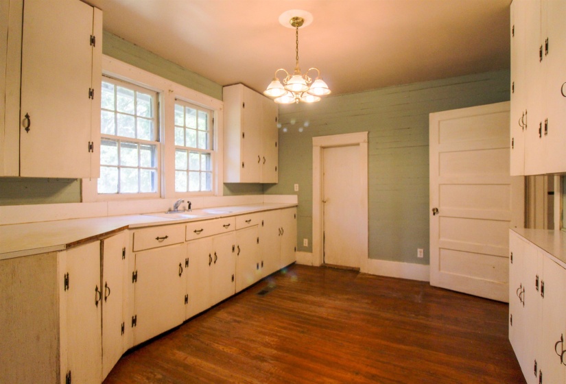 Kitchen featuring light countertops, pendant lighting, dark wood-style flooring, and a chandelier