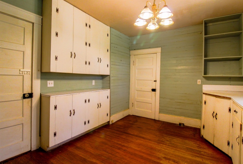 Kitchen featuring open shelves, light countertops, dark wood-type flooring, white cabinets, and wooden walls