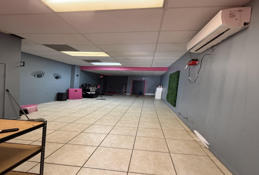 Game room with a wall mounted air conditioner, light tile patterned flooring, and a paneled ceiling